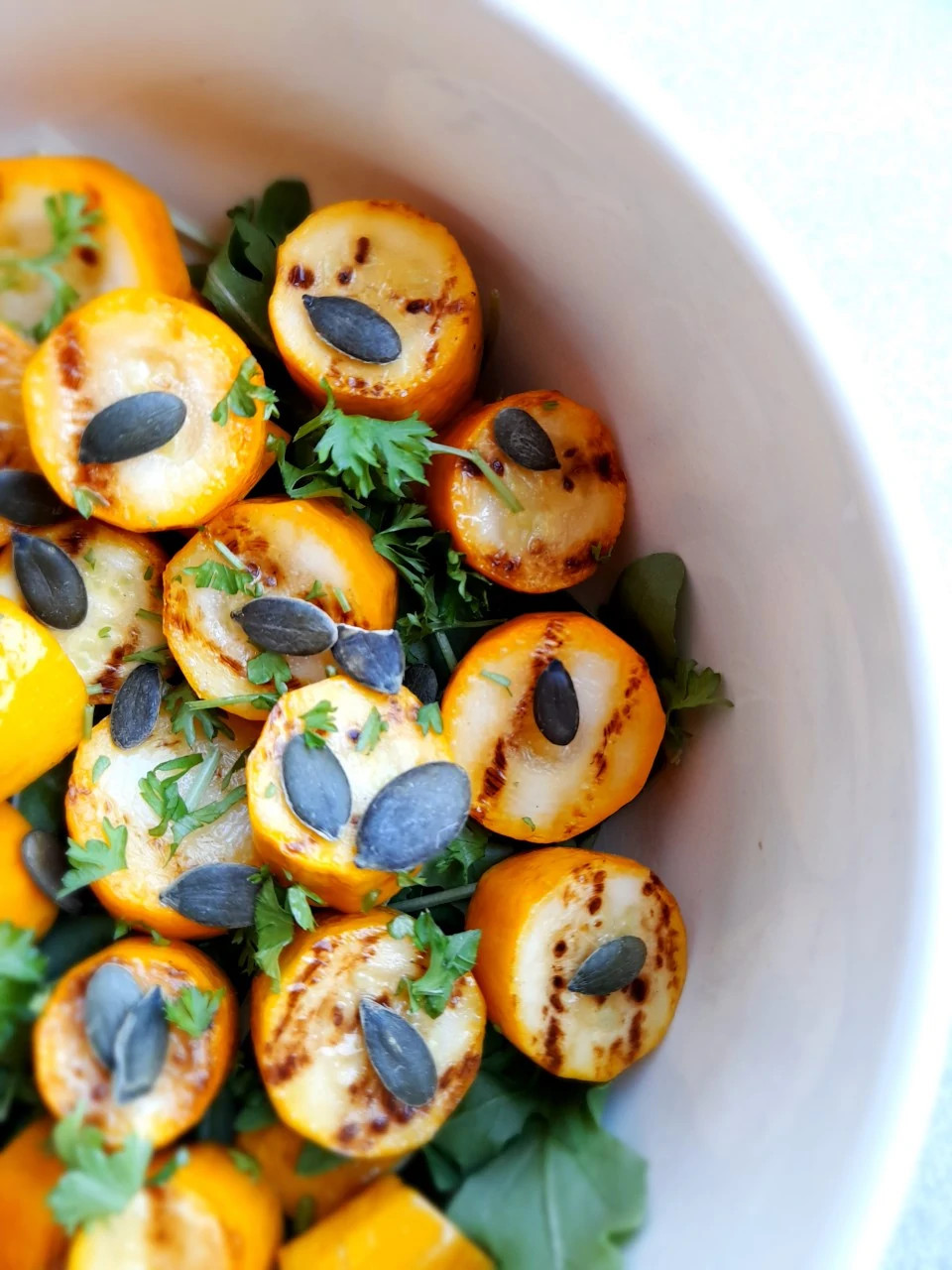 Gegrilde courgette met knoflookolie, peterselie en pompoenpitten